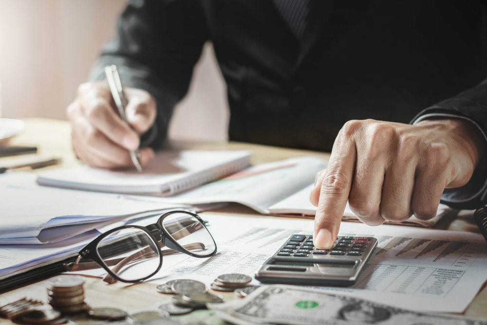 Man making calculations on a calculator (Slash Taxes with Reasonably Low Salary for S Corporation Owner)